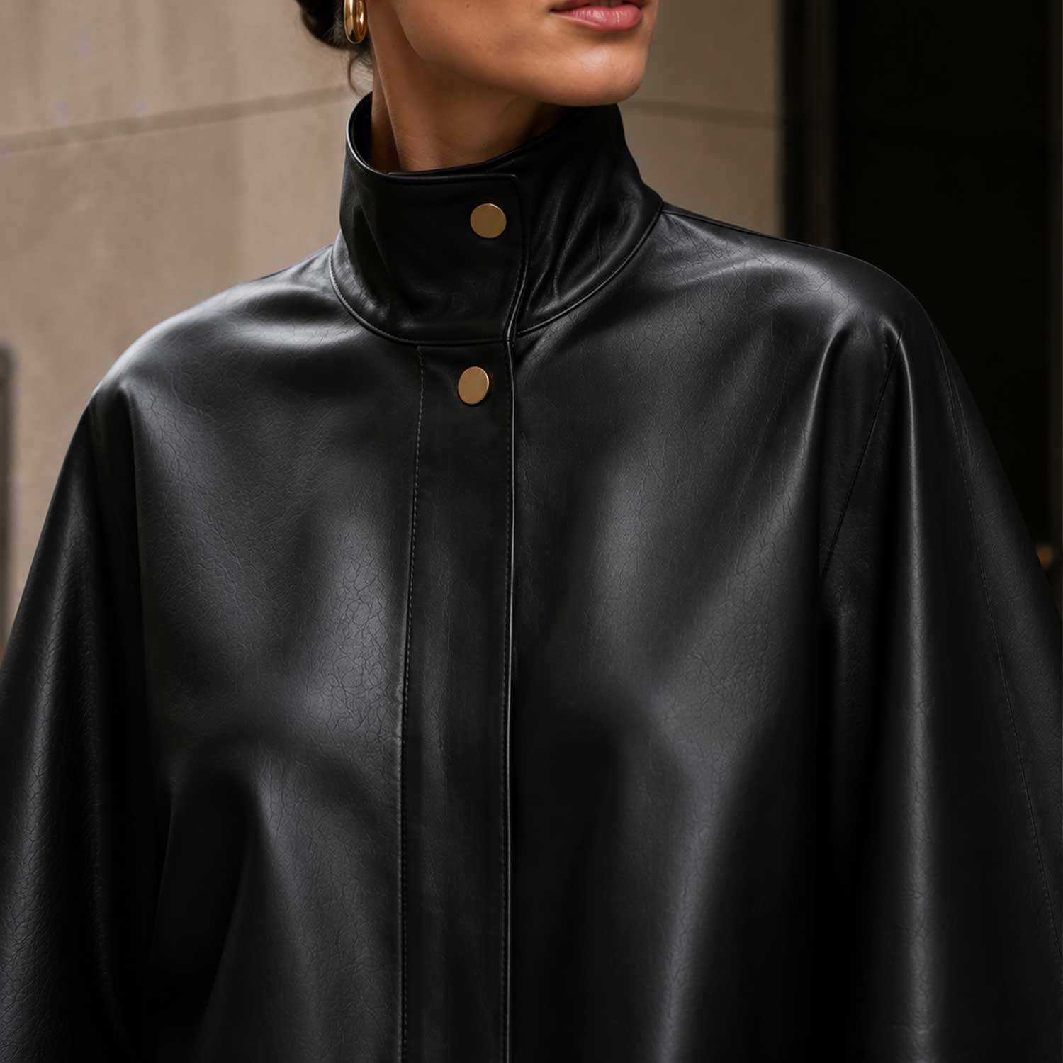 Front view of black sheepskin leather cape jacket with high-neck collar.
Side profile of genuine black leather cape with red satin lining.
Back view of handcrafted sheepskin leather cape jacket.
Close-up of high-neck snap-button collar on black leather cape.
Smooth premium sheepskin leather texture detail.
Luxury red satin lining inside black leather cape.
Flat-lay of black leather cape on a light marble table.
Women's luxury black leather cape in an editorial fashion photoshoot.