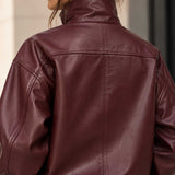 Close-up back view of a person wearing an oversized high-neck leather jacket in deep burgundy.