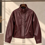 A burgundy faux leather jacket with a stand collar, front zipper, and flap pockets, hanging on a wooden hanger labeled 'SALTO' against a warm beige background.